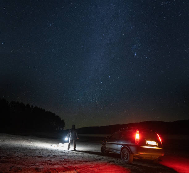 istock Man with car at night stargazing. Getting away from it all. 1464608304