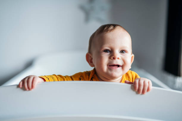 Portrait of charming baby boy looking through his crib.