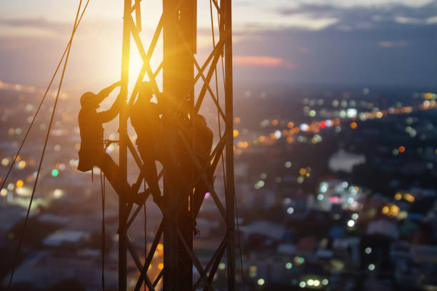 istock Silhouette workers on construction crews to work on high ground heavy industry and connection development, distribution electrical concept. Extension of high-voltage towers on blur city background. 1464608782