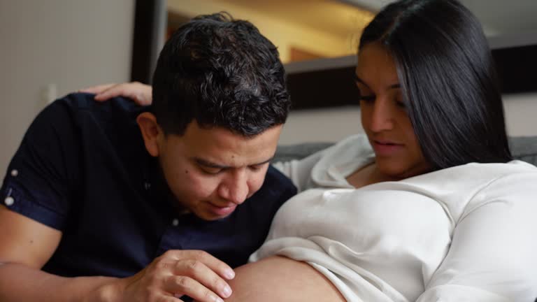 Latin father giving kisses to his pregnant wife's belly.