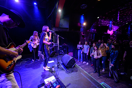 A female fronted rock band performing onstage at a music venue in front of an audience.