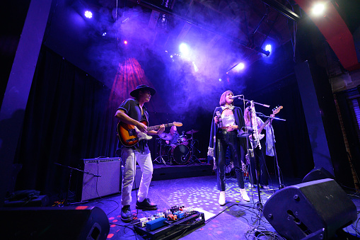 A female fronted rock band performing onstage at a music venue.