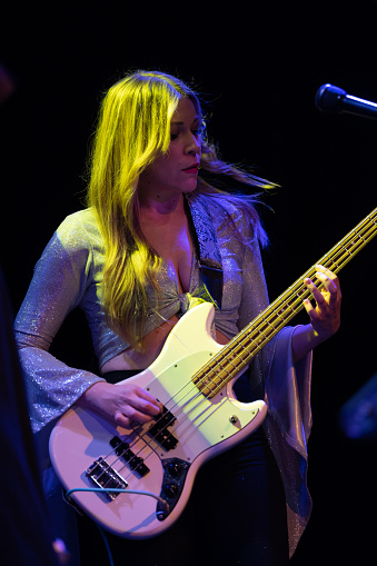 A female fronted rock band performing onstage at a music venue.