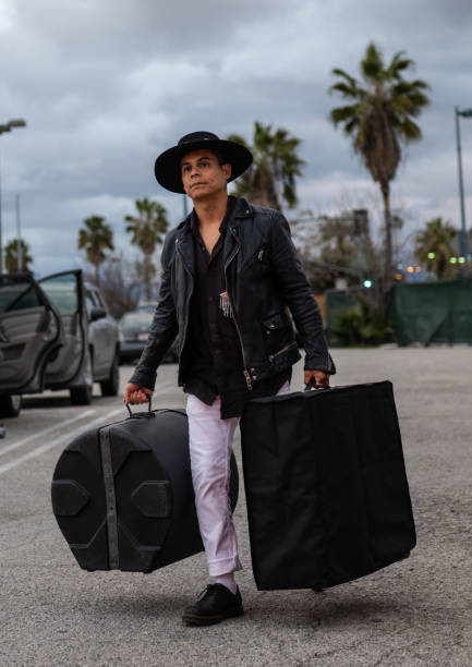 The members of a rock band carrying their instruments and equipment through the parking lot of a music venue before a show.