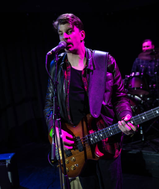 istock Man Singing and Playing Bass Under Pink Stage Light 1464613566