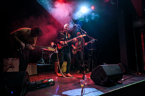 An Americana folk-rock band performing onstage in front of an audience at a live music venue.