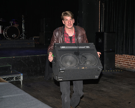 Candid shot of a musician carrying an amp out of a music venue after a show.