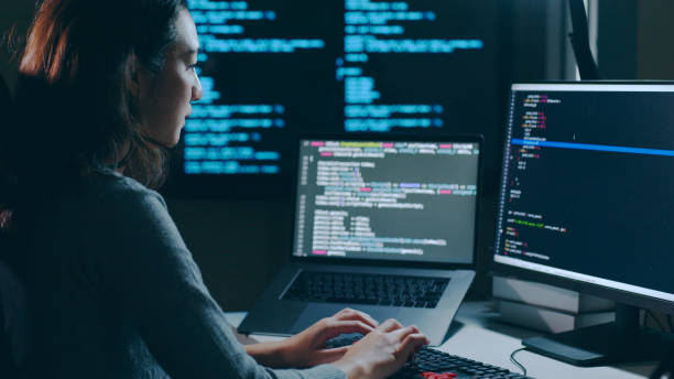 Young Asian woman, developer programmer, software engineer, IT support, working hard at night overtime on computer to check coding in bugging system. stock photo