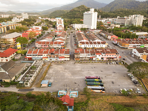an image of a small town with a square used as a depot for sightseeing buses and a row of red-roofed shops and a background of green mountains