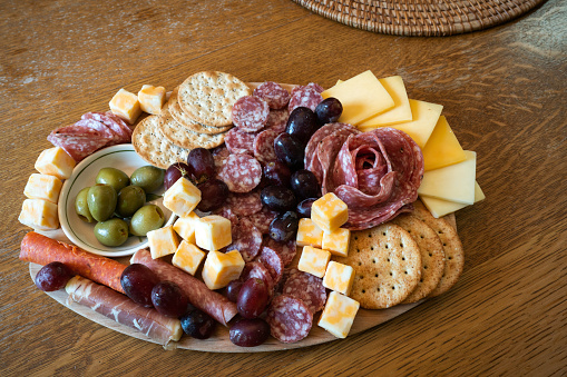 Charcuterie board of olives, cheese, salami, grapes and crackers on a wooden table