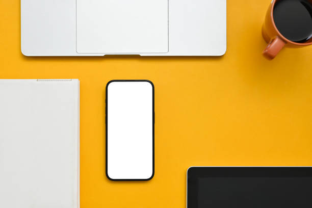 istock Modern creative workspace with smartphone mockup, laptop, and decor on yellow background. 1464640196