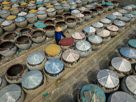 Drone view a working is checking fish sauce brew jars in Mui Ne district, Phan Thiet, Binh Thuan province, central Vietnam