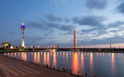 Skyline of Dusseldorf, the capital of the German federal state of North Rhine-Westphalia, in a beautiful sunset with the Rhine on the left and the Pegeluhr and St. Lambertus Basilika on the right.