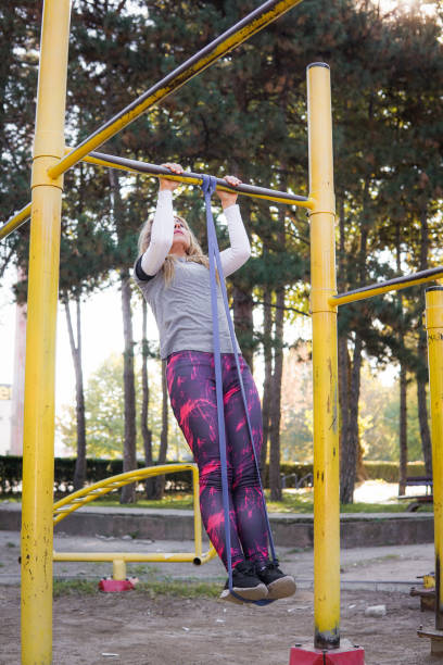 istock Woman doing rubber assisted pull ups out door 1464645999