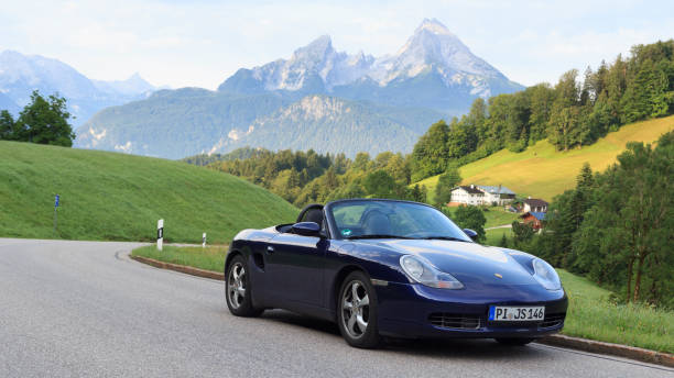 berchtesgaden, niemcy - 25 lipca 2021 r.: niebieski roadster porsche boxster 986 z górą watzmann i panoramą mgły. samochód to dwumiejscowy samochód sportowy z silnikiem umieszczonym centralnie produkowany przez porsche. - germany landscape nissan roadster zdjęcia i obrazy z banku zdjęć