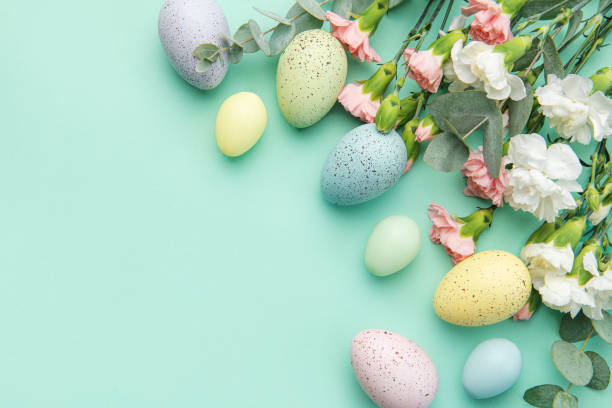 istock Easter colored eggs and a bouquet of white and pink carnations with eucalyptus branches on a soft green background. 1464656352