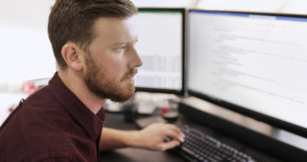 istock Young businessman working on a computer with multiple monitors in an office 1464659252