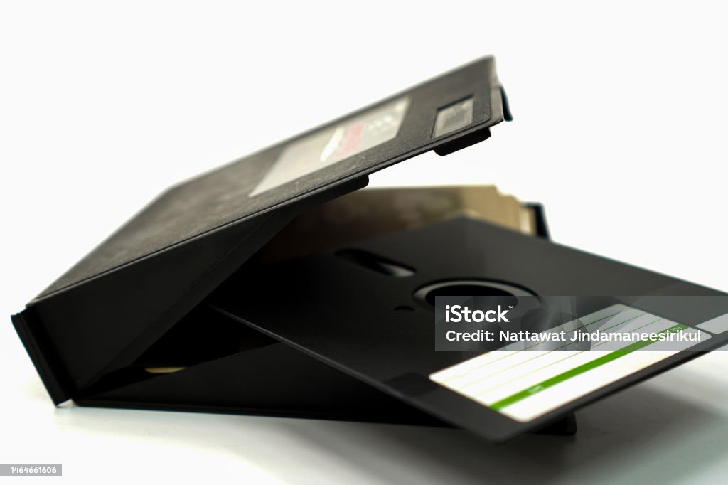A close-up photo shows retro black floppy disks and storage boxes used for computer storage in the 80s-90s on a white background. 1990-1999 Stock Photo