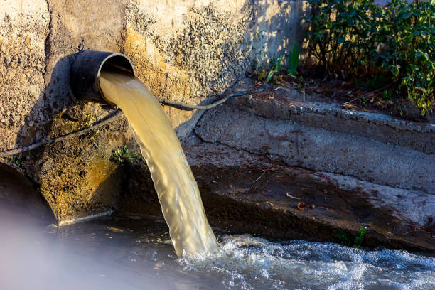 wastewater sewage pipe dumps the dirty contaminated water into the river. water pollution, environment contamination concept - impurities imagens e fotografias de stock