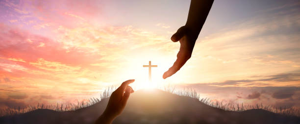 God's helping hand and cross on sunset background stock photo