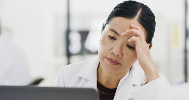 Laboratory, headache and stress scientist woman on laptop for depression research or healthcare data. Mental health, fatigue and burnout scientist person thinking or tired reading report on computer stock photo