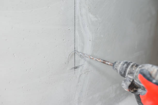 istock Builder electrician makes a hole puncher in a concrete wall for installation of electrical cables 1464666874