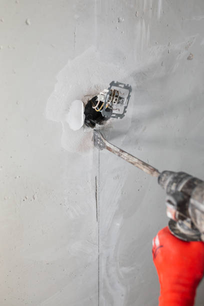 istock Builder electrician makes a hole puncher in a concrete wall for installation of electrical cables 1464666945