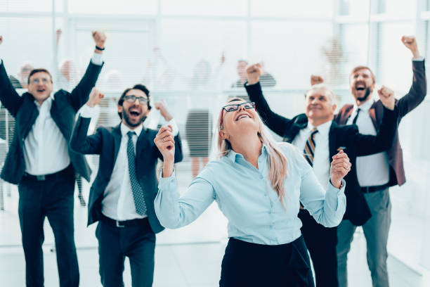 istock jubilant group of employees standing in the office. 1464668377
