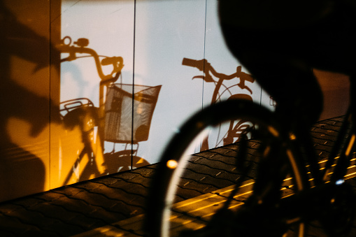 A person riding a bicycle and a shadow on the wall
