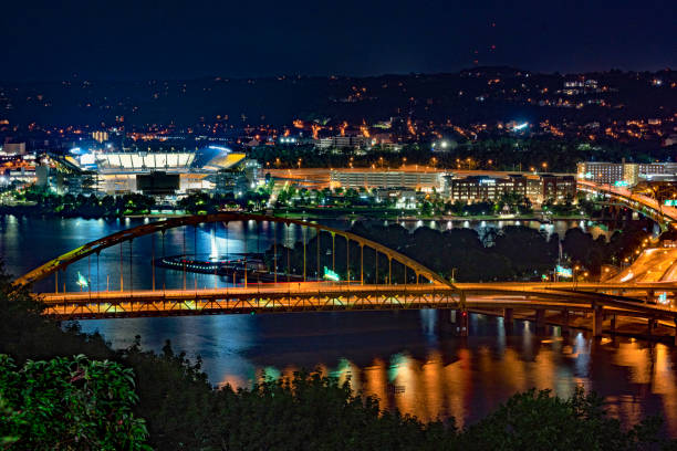 Pittsburgh, Pennsylvania, USA - August 10, 2022: Overview of the city from Mt. Washington above Clemente bridge and the ball stadium at night.