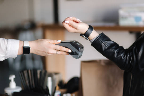 istock Female customer making wireless or contactless payment using smartwatch. Closeup of hands during payment. Store worker accepting payment over nfc technology 1464675106