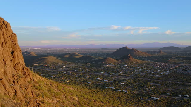 Cinematic aerial shot passing rocky peaks of desert mountains revealing Tucson Arizona, POV drone