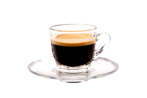 Crema of black coffee in a clear glass on a white background, selective focus, soft focus.