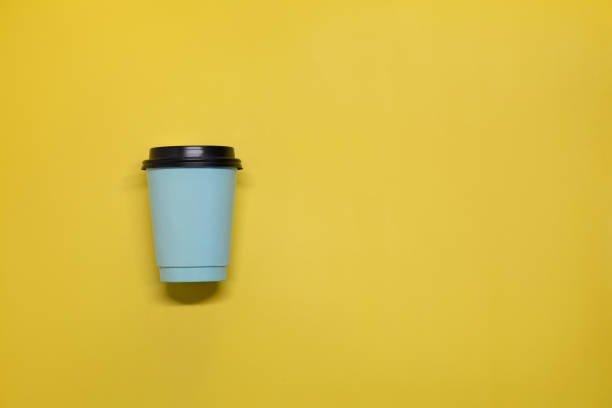 Paper cup with coffee on a yellow background on the left. Paper cup with coffee on a yellow background on the left tasse café stock pictures, royalty-free photos & images