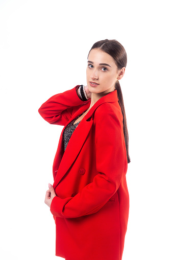 A young woman in a red trouser suit and a shiny top poses on a white background