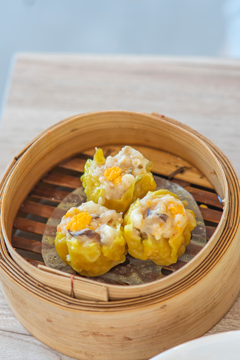 Close-up, top view of traditional Asian/Chinese dumplings in blue plate with soy sauce and chopsticks on gray rustic stone background. Authentic Chinese cuisine