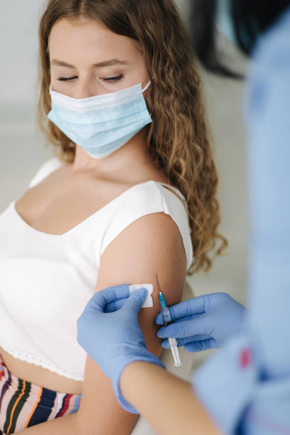 istock Close-up of doctor in protective gloves holding syringe and using cotton before make injection to patient in medical mask. Covid-19 or coronavirus vaccine 1464685212