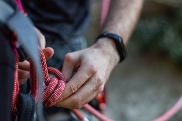 istock Alpinist tying a rope on his climbing equipment 1464686462