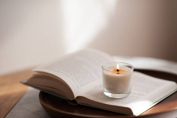 istock Scented candle on paper open book on wooden tray 1464687358