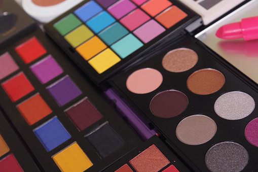 A closeup shot of brightly coloured cosmetic pigmented eye shadows with lipsticks for the best makeup