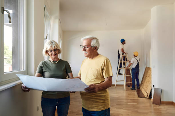 istock Happy mature couple reading blueprints during home renovation process. 1464688803