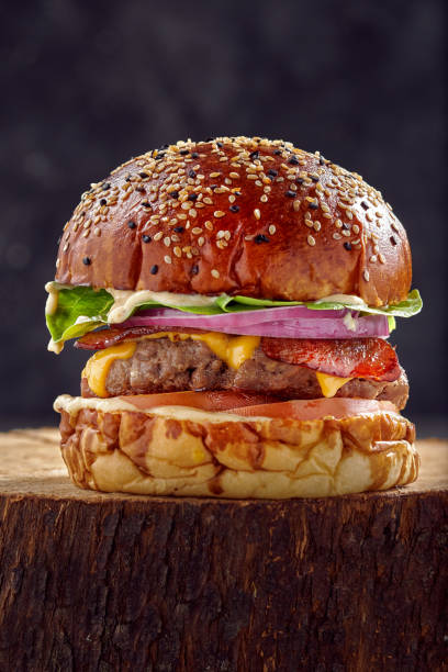 istock Vertical closeup of a burger on the stump with dark blurred background 1464688805