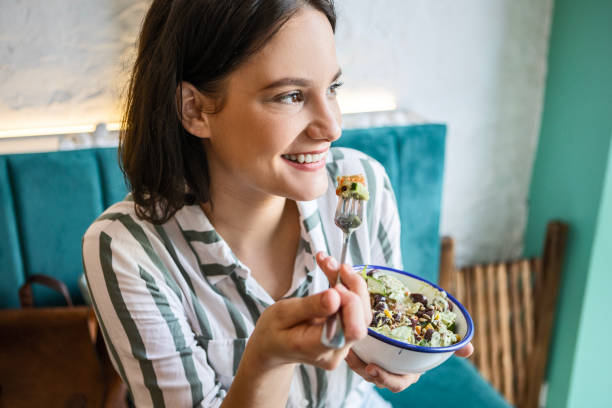 istock Smiling young woman eating salad 1464689015