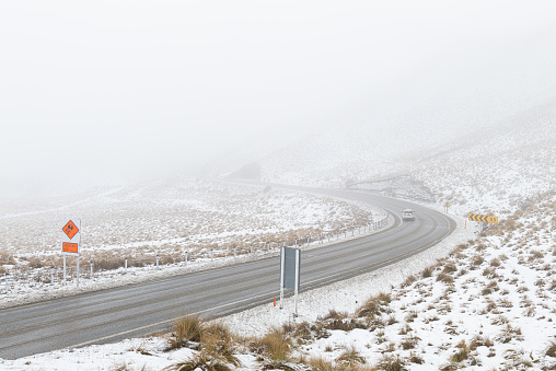 A curvy road in the mountains on a snowy, foggy winter day