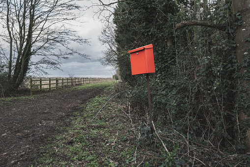Impromptu red letter box seen outside a rural cottage along a dirt track.