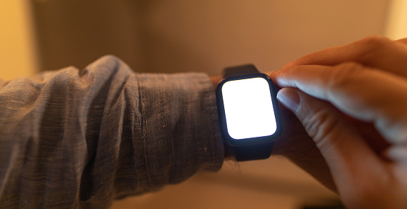 A closeup shot of a businessman looking at hand watch with a blank screen