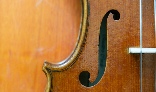 A closeup shot of the f-hole on a violin on a wooden background