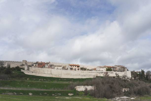 istock Cuellar village and its wall surrounded by green fields under a blue sky with clouds, Spain 1464690794
