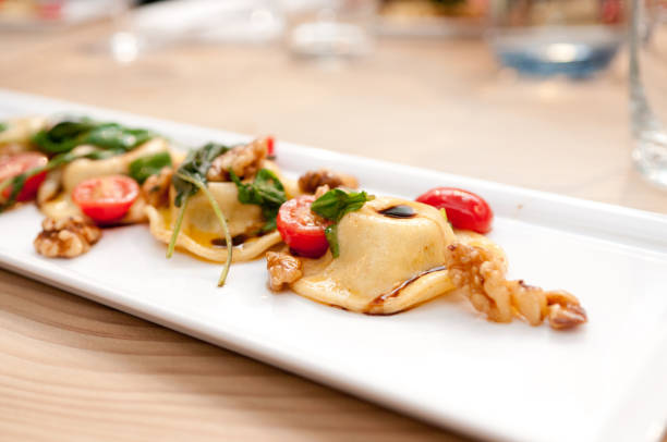 Closeup shot of dumplings decorated with tomatoes on a white plate