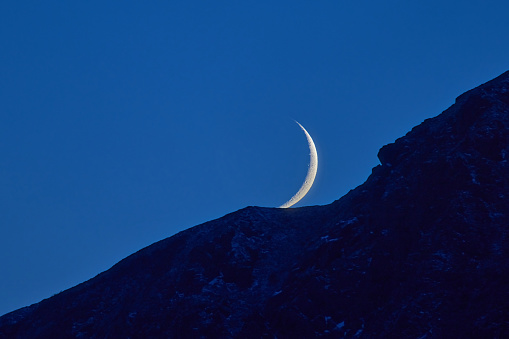 Crescent moon over mountains during the night in Norway, Lofoten.